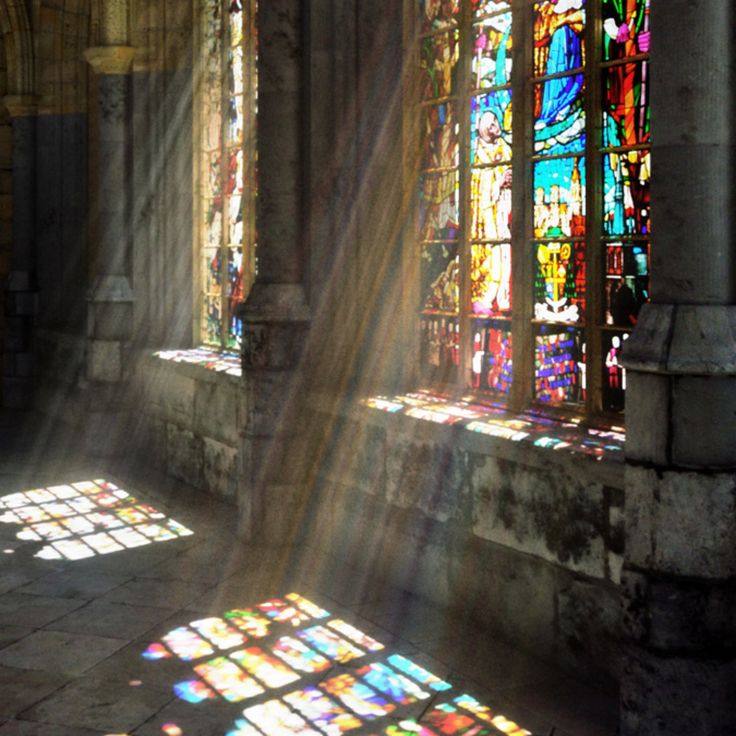 sunbeams and colored reflections falling through a stained-glass window onto a stone floor